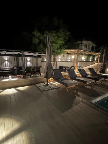an umbrella and lounge chairs next to a pool at night at Magic View Luxury Villa 4u - Spiro Spero in Kineta