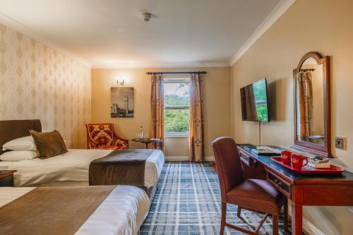 a hotel room with two beds and a desk at Muthu Belstead Brook Hotel in Ipswich