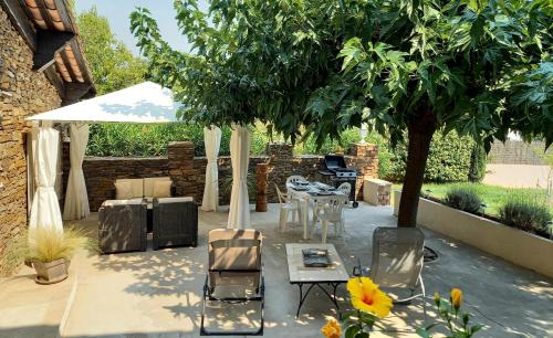 d'une terrasse avec une table, des chaises et un arbre. dans l'établissement T2 de charme 55 m² au calme avec terrasse ombragée 40m2, à Carnoules