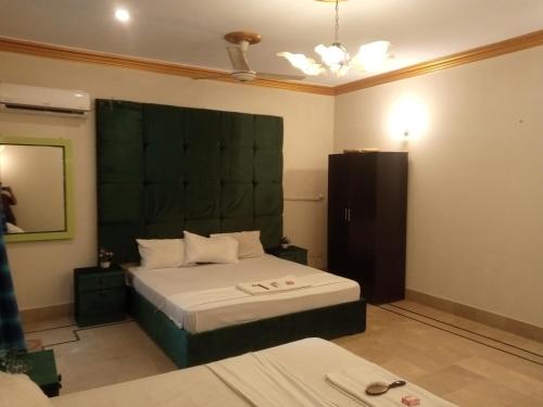 a bedroom with a bed with a green headboard at Johar Hill view Guest House in Karachi