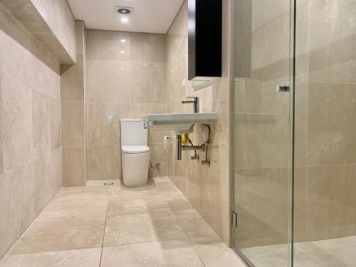 a bathroom with a toilet and a glass shower at Putney Studio, short drive to parklands & Olympic Park in Sydney