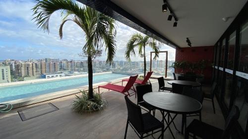 a balcony with tables and chairs and a swimming pool at Sky Concept in Maceió