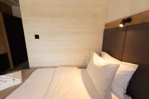 a bedroom with a bed with white sheets and pillows at Hotel M Star Novi Pazar in Novi Pazar