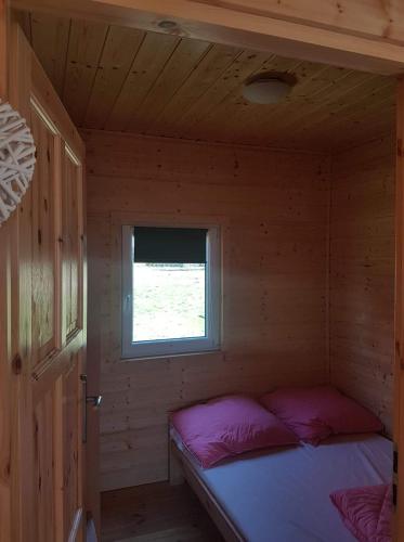 a small bedroom with a bed in a wooden cabin at Dolina Rusinowa in Rusinowo