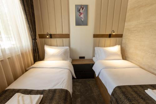 two beds in a hotel room with white sheets at Hotel M Star Novi Pazar in Novi Pazar