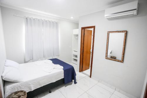Habitación blanca con cama y espejo en Apto Taperapuan 2 quartos com piscina perto praia, en Porto Seguro