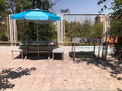 a table with a blue umbrella and two chairs at Jrvezh House in Yerevan