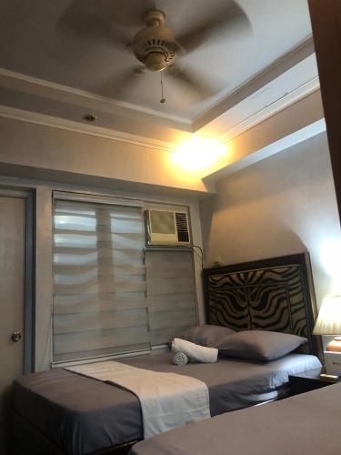 a bedroom with two beds and a window with a fan at 2 separate fully furnished condo units 1BR on the 23rd flr and 3BR penthouse on the 41st flr, with different bookings and daily rates in Ermita, Manila near SLEC,US Embassy, Mall and Parks in Manila