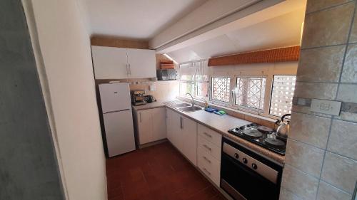 a small kitchen with white cabinets and a stove at Ocean Walk Manta in Zinkwazi Beach