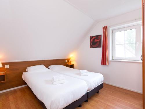 two beds in a small room with a window at Nice holiday home in Hellendoorn with terrace in Hellendoorn