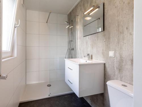 uma casa de banho branca com um lavatório e um chuveiro em Stylish chalet with a dishwasher, in a holiday park at a recreational lake em Lathum