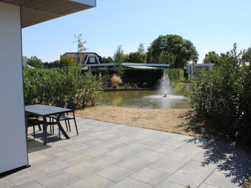 a patio with a table and a pond with a fountain at Chalet with Pond View in Gelderland in Lathum