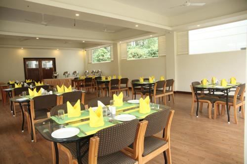 una sala da pranzo con tavoli e sedie con tovaglioli gialli sopra di Peppervine Hotel a Thekkady