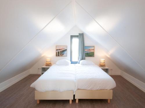 1 dormitorio con cama blanca y ventana en Modern design lodge with combi microwave, in national park en Tholen