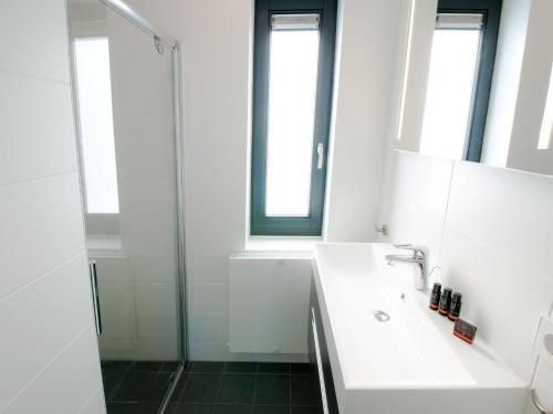 a white bathroom with a sink and a shower at Modern design lodge with combi microwave, in national park in Tholen