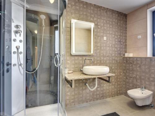 a bathroom with a shower and a sink and a toilet at Luxury villa with private pool, terrace and BBQ in Valbandon