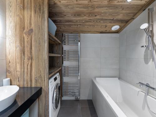 une salle de bain avec baignoire et machine à laver dans l'établissement Appartement familial neuf à Courchevel près des commerces et pistes - FR-1-562-65, à Courchevel