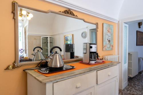 Villa Boschetti Apartments في مونوبولي: مرآة على منضدة مع آلة صنع القهوة عليه