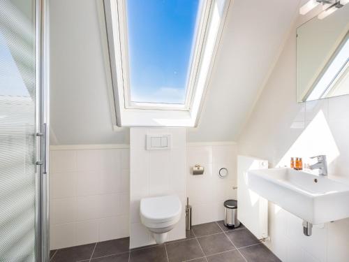 a bathroom with a toilet sink and a skylight at Modern design lodge with combi microwave, in national park in Tholen
