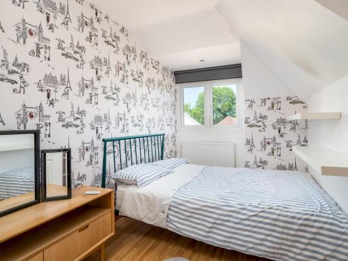 1 dormitorio con 1 cama y pared cubierta de papel pintado en Pass the Keys Charming 3 bed house with parking and large garden, en Radlett