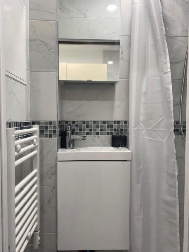 uma cozinha branca com um lavatório e um espelho em AgíaHouse - Aubervilliers em Aubervilliers