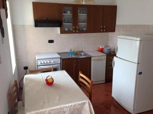 a kitchen with a table and a white refrigerator at Apartmani Lucija in Vrata
