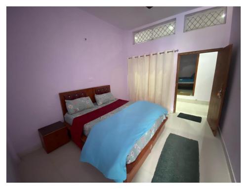 Schlafzimmer mit einem Bett mit blauer Bettwäsche und einem Fenster in der Unterkunft Badrinath Jb Laxmi hotel in Badrīnāth