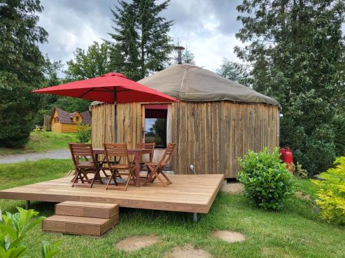 - un kiosque avec des chaises et une table avec un parasol rouge dans l'établissement les Refuges du Chalet, à Sart-lez-Spa