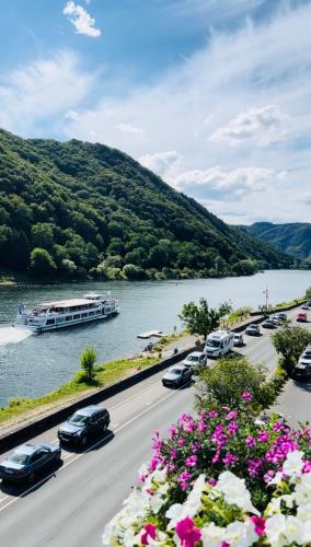 a river with cars and a boat in the water at Hotel St. Georg in Ediger-Eller