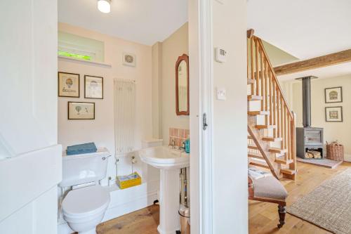 a bathroom with a toilet and a sink and a staircase at Beech Cottage in Honiton