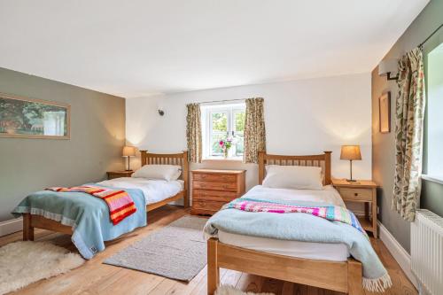 1 dormitorio con 2 camas y ventana en Beech Cottage en Honiton