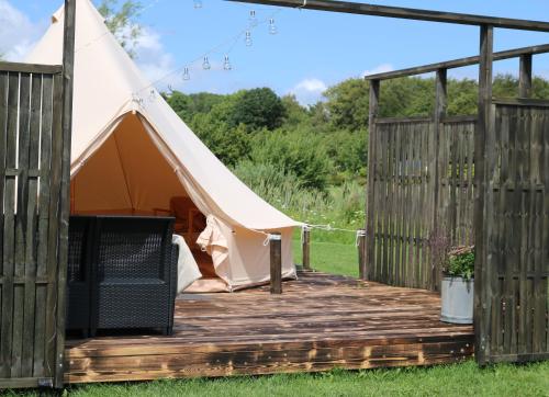 a tent with a wooden deck in a field at Haramara Tipi in Vester-Skerninge