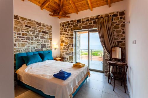 a bedroom with a bed with a stone wall at Stonevillas and Seaview Garden Marion in Agnándion