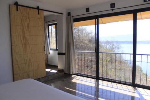 a bedroom with a large window with a view of the water at Yauik in Tequesquitengo