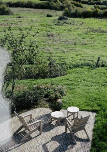 two chairs and a table on a patio with a field at The Shepherds Farm in Heuvelland