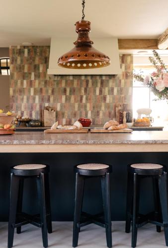 a kitchen with three bar stools at a counter at The Shepherds Farm in Heuvelland