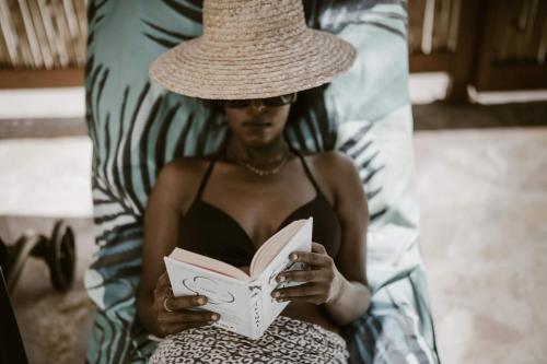 Una donna con un cappello di paglia che legge un libro di Kanela Cottages ad Alikanás