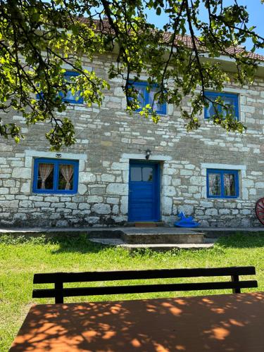 un edificio de piedra con una puerta azul y un banco en Etno kuća Krvavac en Pljevlja