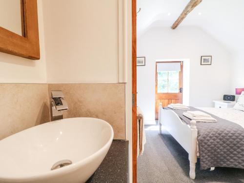 a bathroom with a tub and a bedroom with a bed at The Dell in Winster