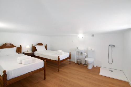 two beds in a room with a shower and a toilet at Quinta Alegre Tavira T3 in Luz de Tavira