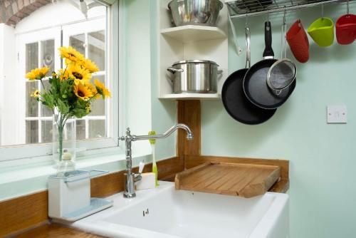um lavatório de cozinha com um vaso de flores e um vaso em 3BR house a perfect group getaway em Londres