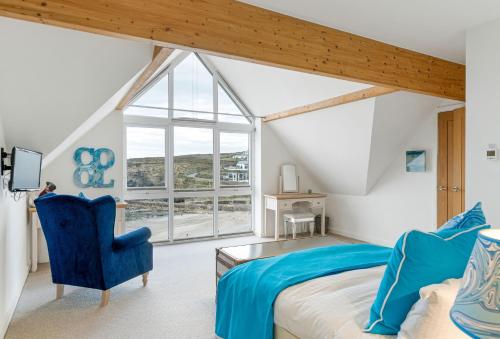 1 dormitorio con 1 cama y 1 silla azul en The Lookout, en Portreath