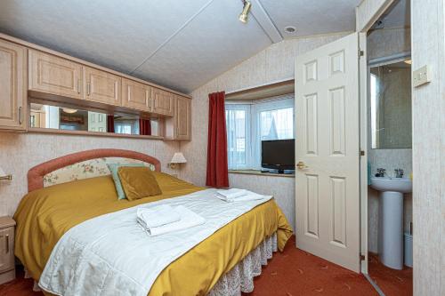 1 dormitorio con 1 cama grande y lavamanos en Caravan at Ysgubor, en Tregarth