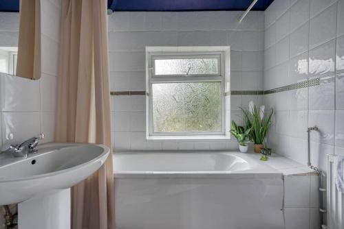 a bathroom with a tub and a sink and a window at Stylish Home - Fast Wi-Fi-FREE Parking in Nottingham