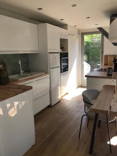 a kitchen with white cabinets and a wooden table at Calme & jolie maison près de Paris in Nanterre