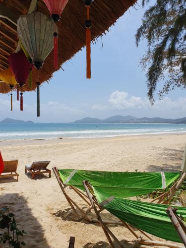 a beach with a green hammock and chairs on the sand at Lucky Spot Beach Bungalow in Song Cau