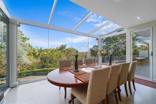 a dining room with a table and chairs and glass windows at GRAND APARTMENT by the Harbor in Sydney
