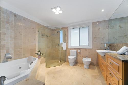 ein Badezimmer mit einer Badewanne, einem Waschbecken und einem WC in der Unterkunft House by the Harbor in Sydney