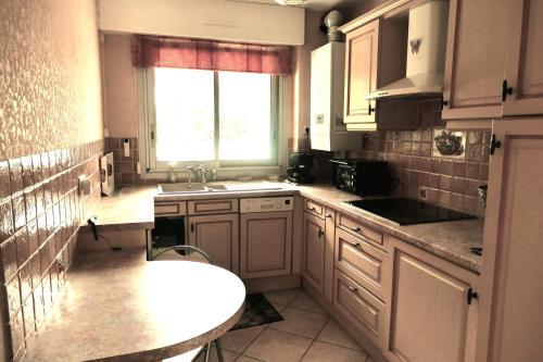 uma cozinha com armários brancos, um lavatório e uma janela em Cosy cocoon with terrace near the sea em Arcachon