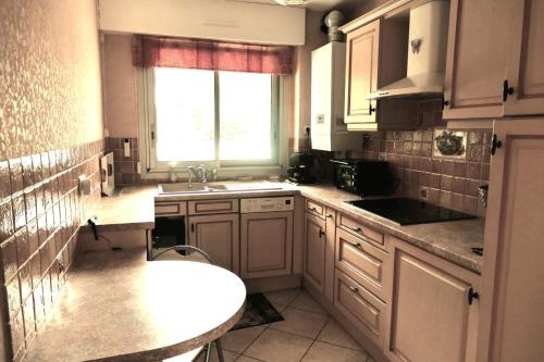 a kitchen with white cabinets and a sink and a window at Cosy cocoon with terrace near the sea in Arcachon